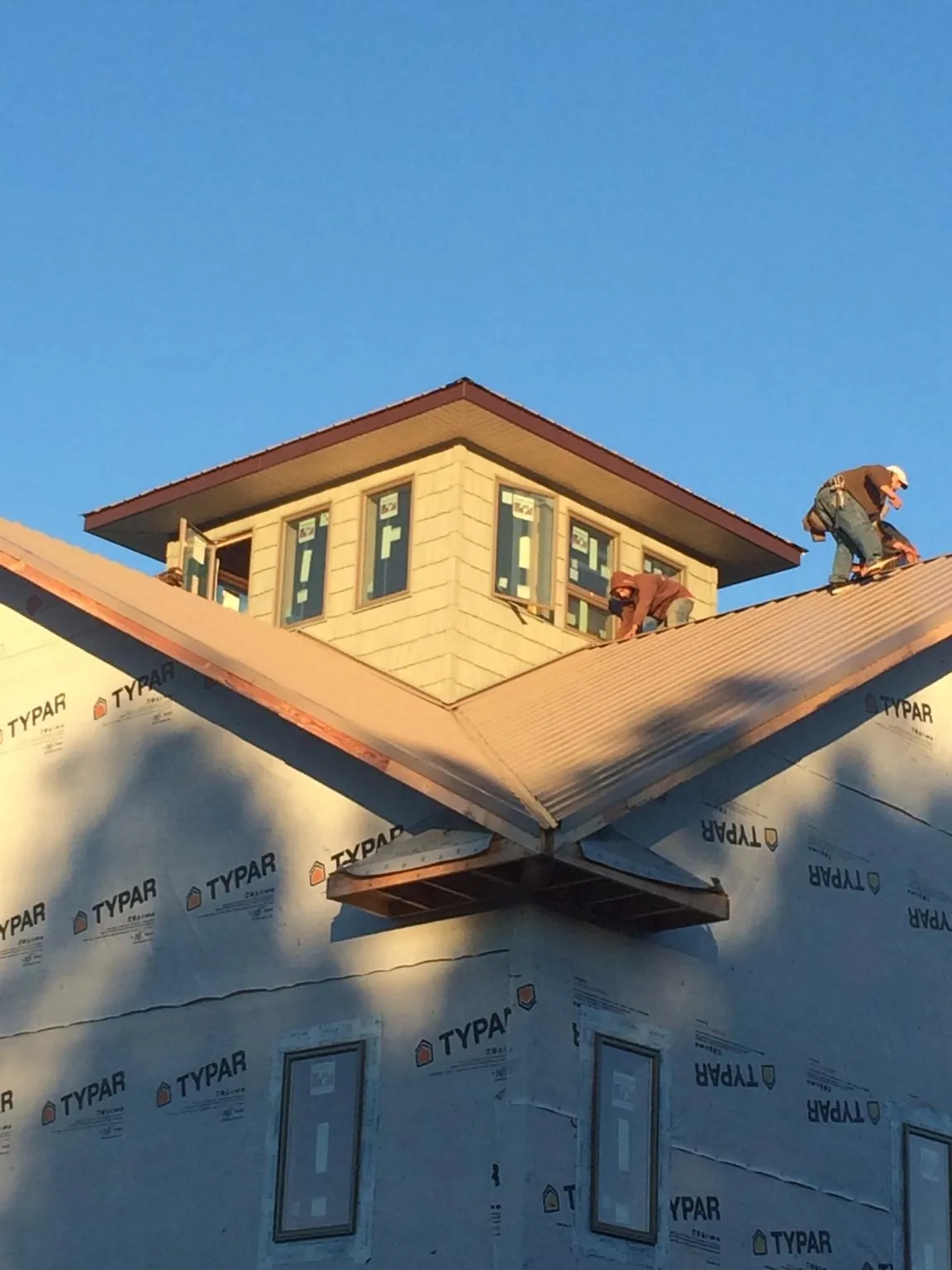 Roofers working around a rooftop cupola on a new metal roof at sunset — Roof Waterproofing in Brodhead by Roofing Brothers